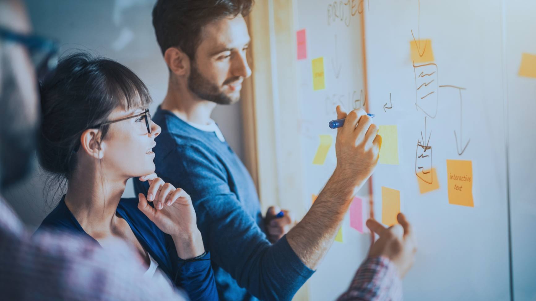 Creative team brainstorming with sticky notes on a glass wall in a vibrant office environment.